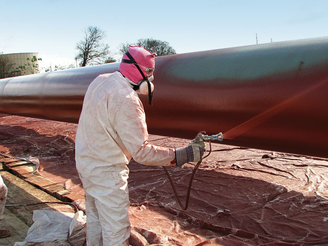 Worker applying a coating to an exposed pipeline