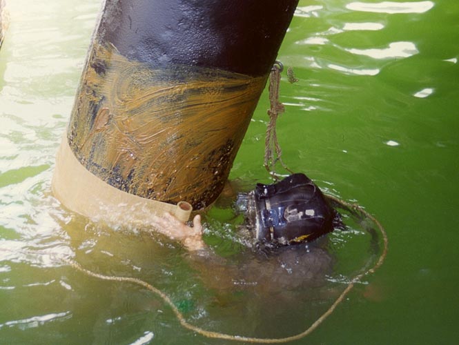 Steel pilings being wrapped with a marine grade petrolatum wax tape from Denso