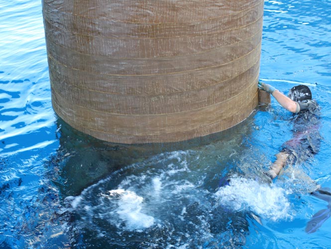 Large diameter marine steel pile being protected from splashzone corrosion with Denso products